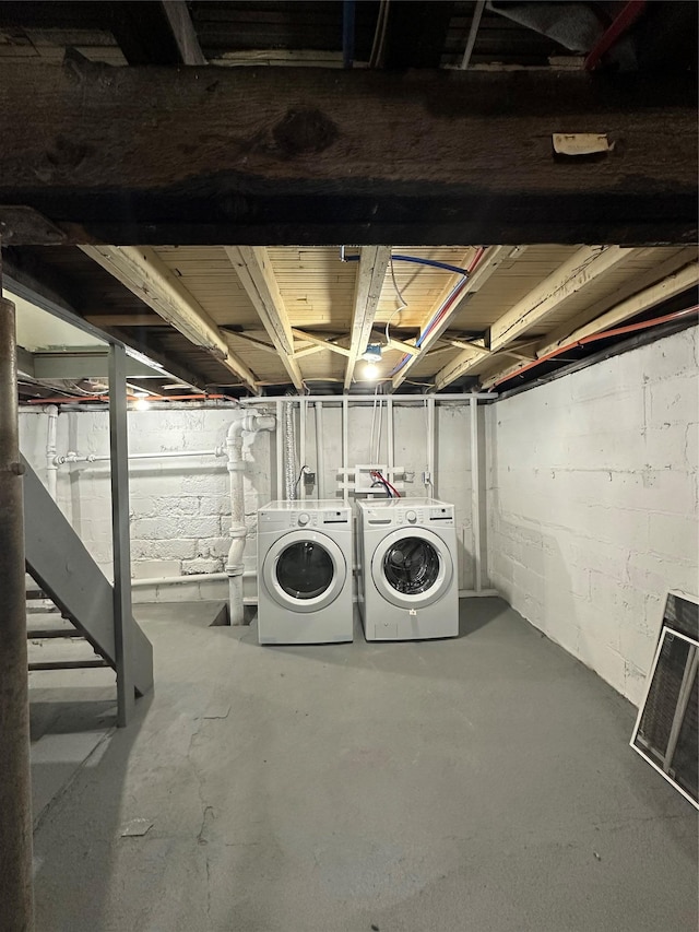 unfinished basement featuring independent washer and dryer, concrete block wall, and heating unit