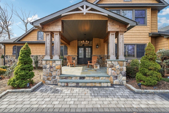 doorway to property with a porch, french doors, and stone siding