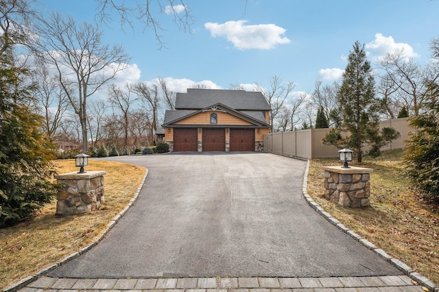 exterior space featuring stone siding, driveway, and fence