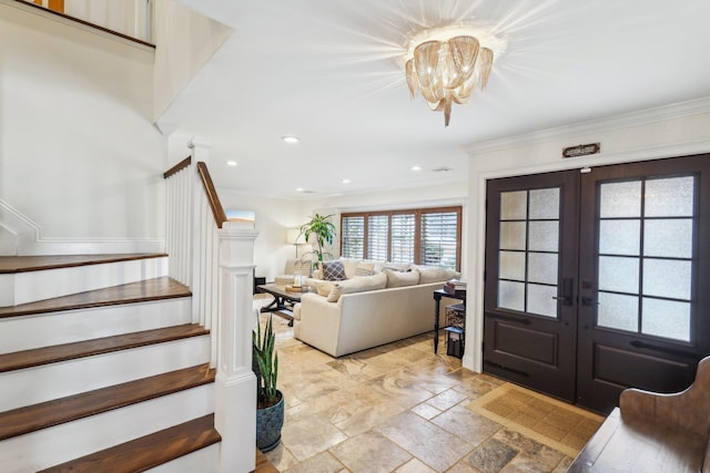 foyer entrance with ornamental molding, stone tile flooring, french doors, an inviting chandelier, and stairs