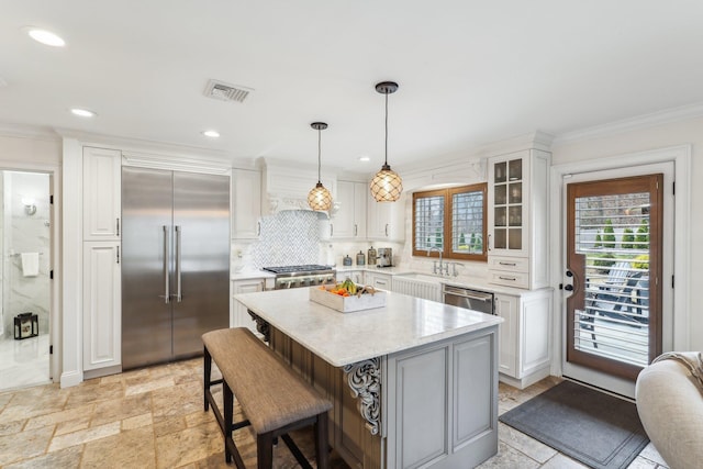 kitchen with visible vents, ornamental molding, decorative backsplash, stone tile flooring, and appliances with stainless steel finishes