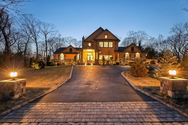 view of front of house with stucco siding, a chimney, and curved driveway