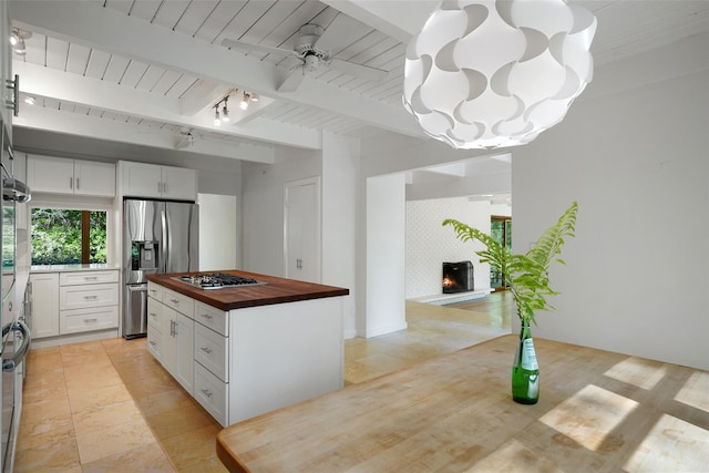 25 Moseman Ave, Katonah, NY 10536 - kitchen featuring butcher block counters, stainless steel appliances, white cabinetry, a large fireplace, and beam ceiling