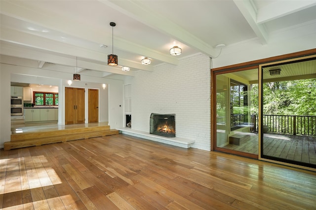 25 Moseman Ave, Katonah, NY 10536 - unfurnished living room featuring wood-type flooring, beam ceiling, a brick fireplace, and brick wall