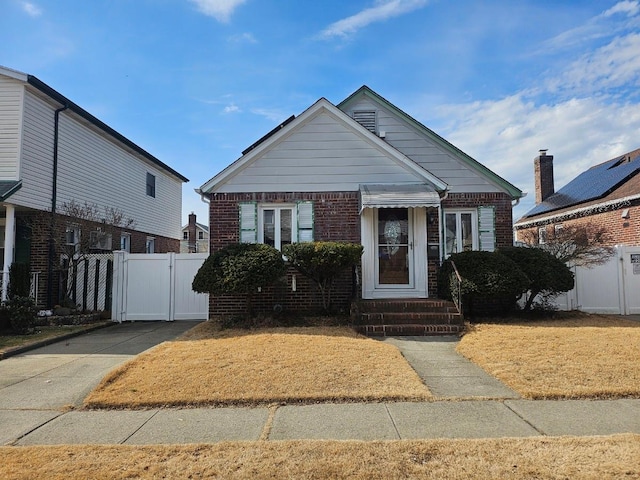 bungalow featuring entry steps, brick siding, fence, and a gate