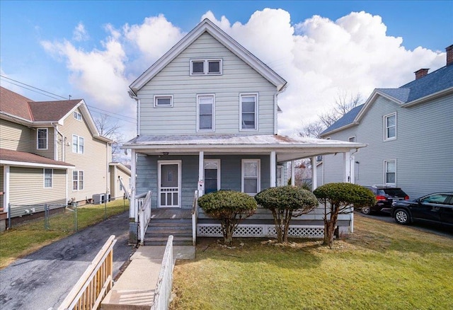 view of front facade with central AC unit, covered porch, a front lawn, and fence