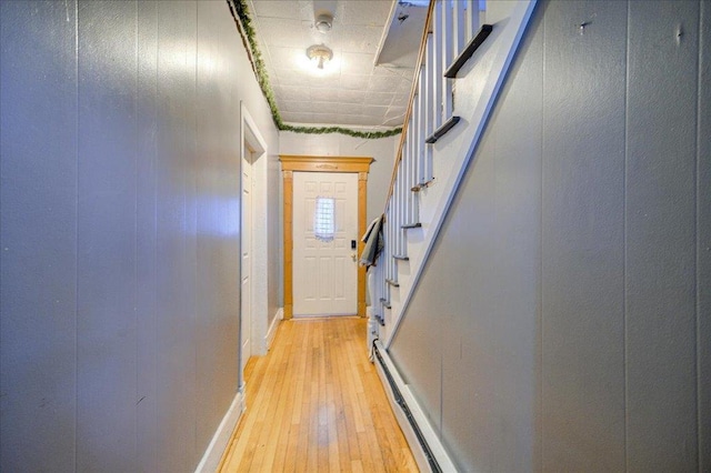 doorway featuring a baseboard radiator, baseboards, light wood-style flooring, and stairway