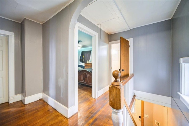 hallway with arched walkways, crown molding, and wood finished floors