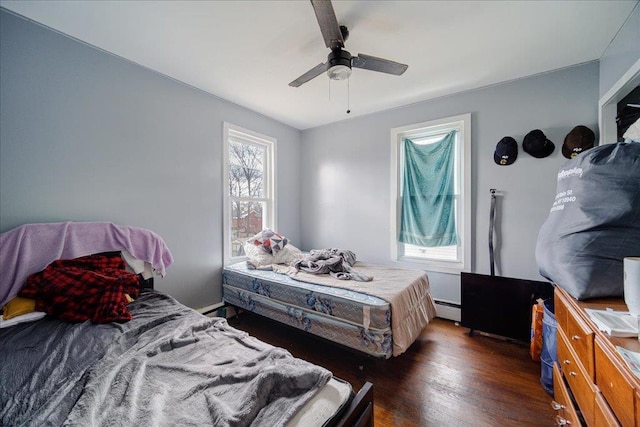 bedroom with a baseboard radiator, wood finished floors, and a ceiling fan