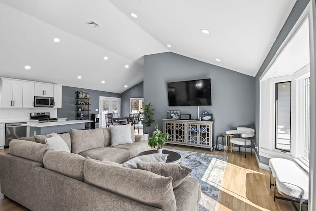 living room with recessed lighting, visible vents, lofted ceiling, and wood finished floors