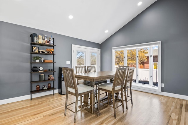 dining space with recessed lighting, light wood-style flooring, high vaulted ceiling, and baseboards