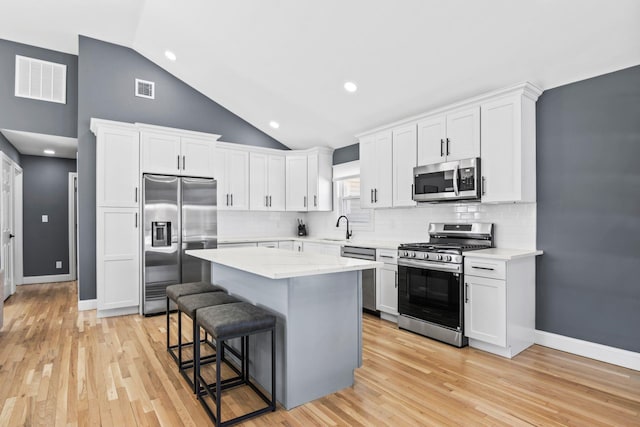 kitchen featuring a breakfast bar, white cabinetry, visible vents, and appliances with stainless steel finishes