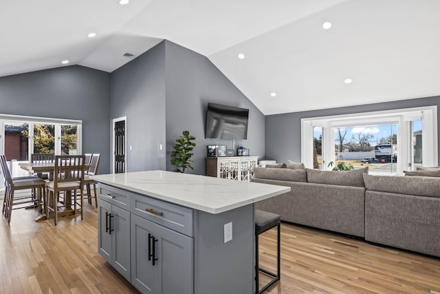 kitchen featuring gray cabinetry, a center island, open floor plan, a breakfast bar area, and light wood-type flooring