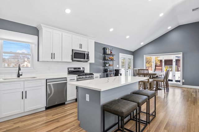 kitchen with a healthy amount of sunlight, a kitchen island, a breakfast bar area, stainless steel appliances, and a sink