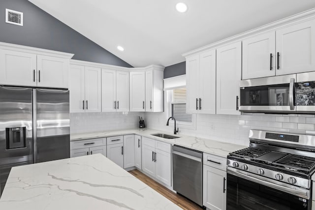 kitchen featuring a sink, lofted ceiling, white cabinetry, and stainless steel appliances