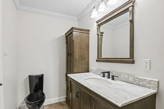 bathroom with vanity, crown molding, wood finished floors, and baseboards