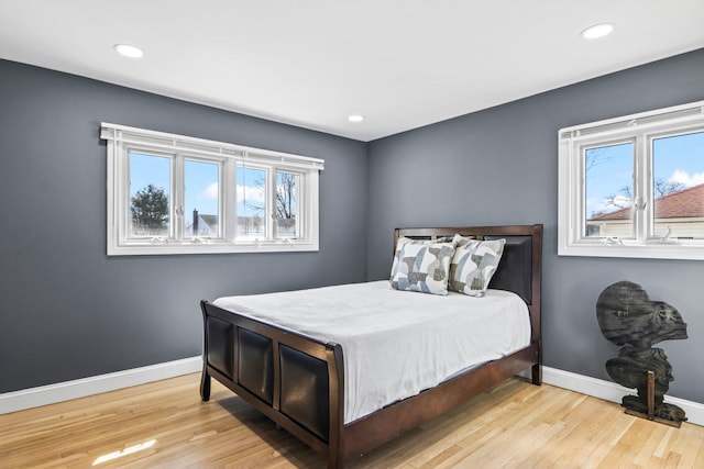 bedroom with multiple windows, wood finished floors, and baseboards