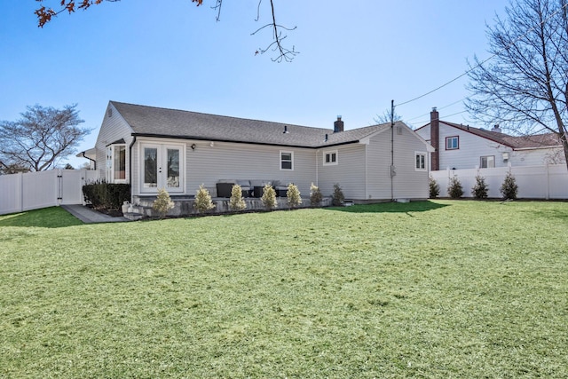 back of house with a lawn, french doors, a fenced backyard, and a gate