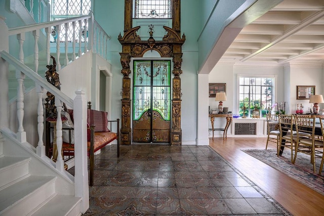 foyer with baseboards, arched walkways, stairway, wood finished floors, and a high ceiling