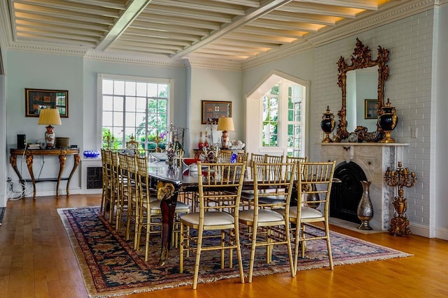 dining space featuring a healthy amount of sunlight, brick wall, and hardwood / wood-style flooring