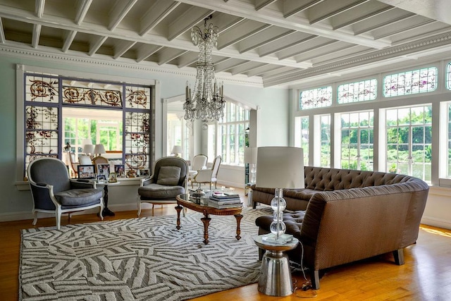 living area featuring baseboards, coffered ceiling, an inviting chandelier, and wood finished floors