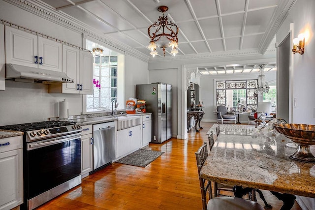 kitchen with appliances with stainless steel finishes, a chandelier, white cabinets, and under cabinet range hood