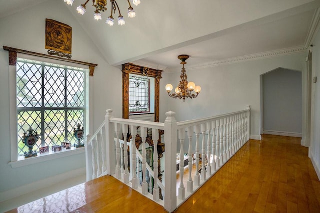 hallway featuring an inviting chandelier, crown molding, wood finished floors, and an upstairs landing