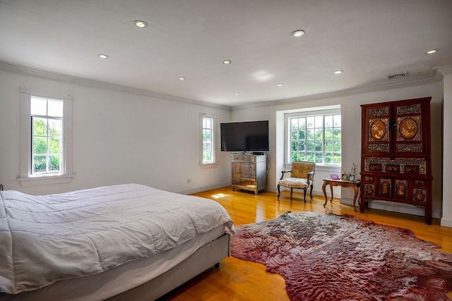 bedroom featuring baseboards, light wood-type flooring, visible vents, and crown molding