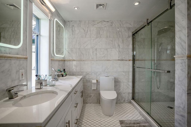 full bath featuring double vanity, a sink, toilet, and a shower stall