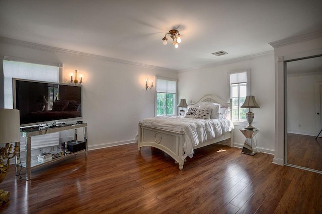 bedroom featuring ornamental molding, wood finished floors, visible vents, and baseboards