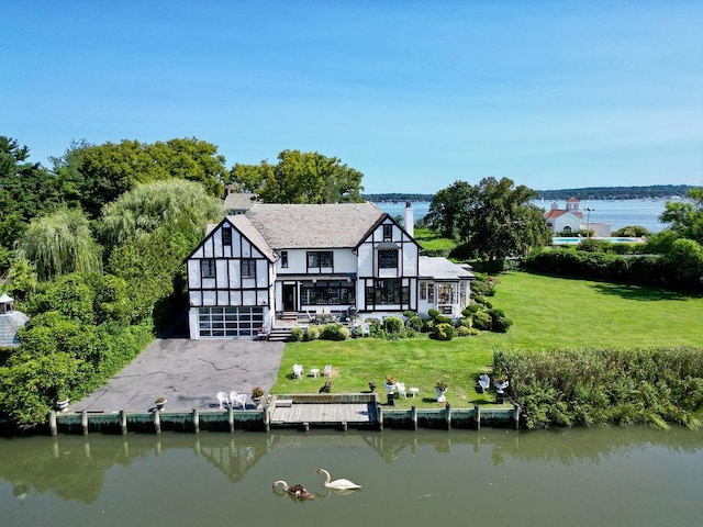 back of house featuring a water view, driveway, and a yard