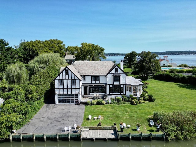 rear view of property with a water view, a lawn, and driveway