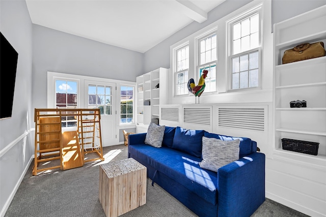 carpeted living room featuring beamed ceiling and built in shelves