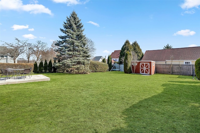 view of yard with an outdoor structure, a storage unit, a fenced backyard, and a patio area