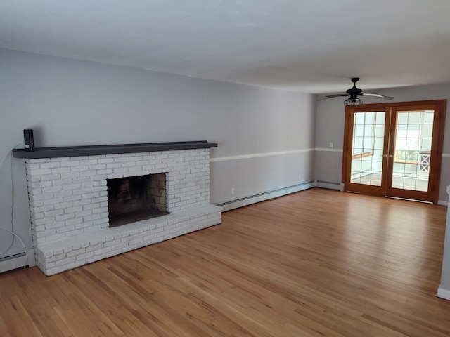 unfurnished living room with a baseboard heating unit, a ceiling fan, a brick fireplace, and wood finished floors