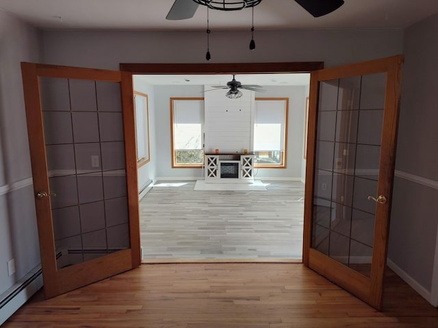 interior space featuring a ceiling fan, a baseboard radiator, baseboards, and wood finished floors