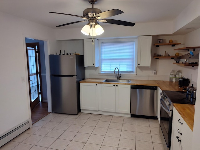 kitchen featuring white cabinets, butcher block counters, a baseboard radiator, appliances with stainless steel finishes, and a sink