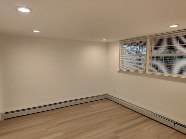 empty room with baseboards, light wood finished floors, a baseboard radiator, and recessed lighting