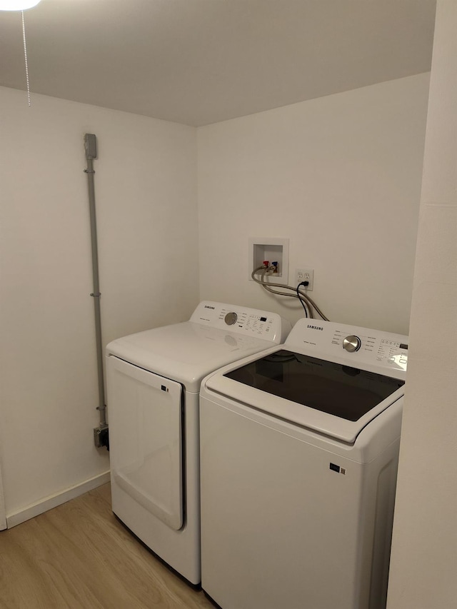 laundry area with laundry area, light wood finished floors, and washing machine and clothes dryer