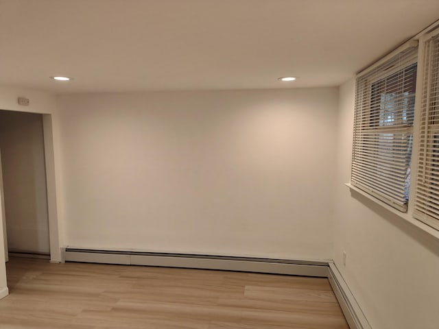 empty room with light wood finished floors, baseboard heating, and recessed lighting