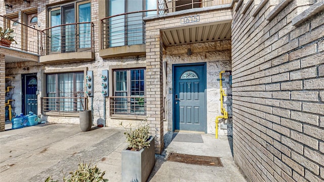 entrance to property featuring brick siding and a balcony