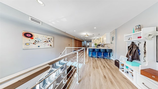 interior space with light wood-style floors, recessed lighting, visible vents, and an upstairs landing