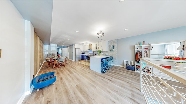 kitchen with stainless steel appliances, light countertops, light wood-style floors, a peninsula, and baseboards