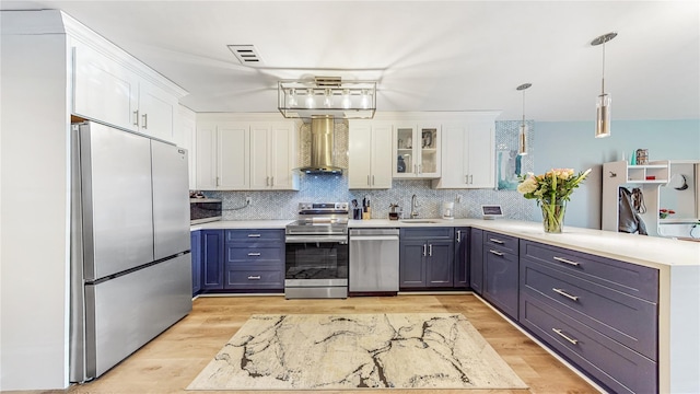 kitchen with stainless steel appliances, white cabinets, a peninsula, and wall chimney exhaust hood