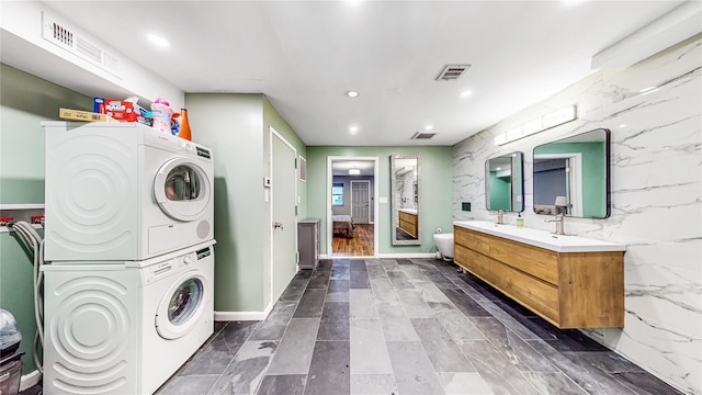 clothes washing area with stacked washer and dryer, recessed lighting, laundry area, and visible vents