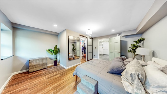 bedroom with recessed lighting, light wood-style flooring, baseboards, and a spacious closet