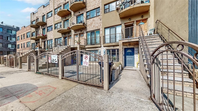 exterior space featuring brick siding, a gate, fence, and stucco siding