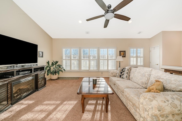 carpeted living area featuring baseboards, ceiling fan, and vaulted ceiling