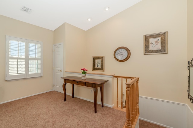 hall featuring baseboards, visible vents, vaulted ceiling, light carpet, and an upstairs landing