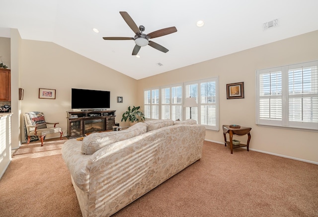 living area featuring a wealth of natural light, visible vents, lofted ceiling, and light colored carpet